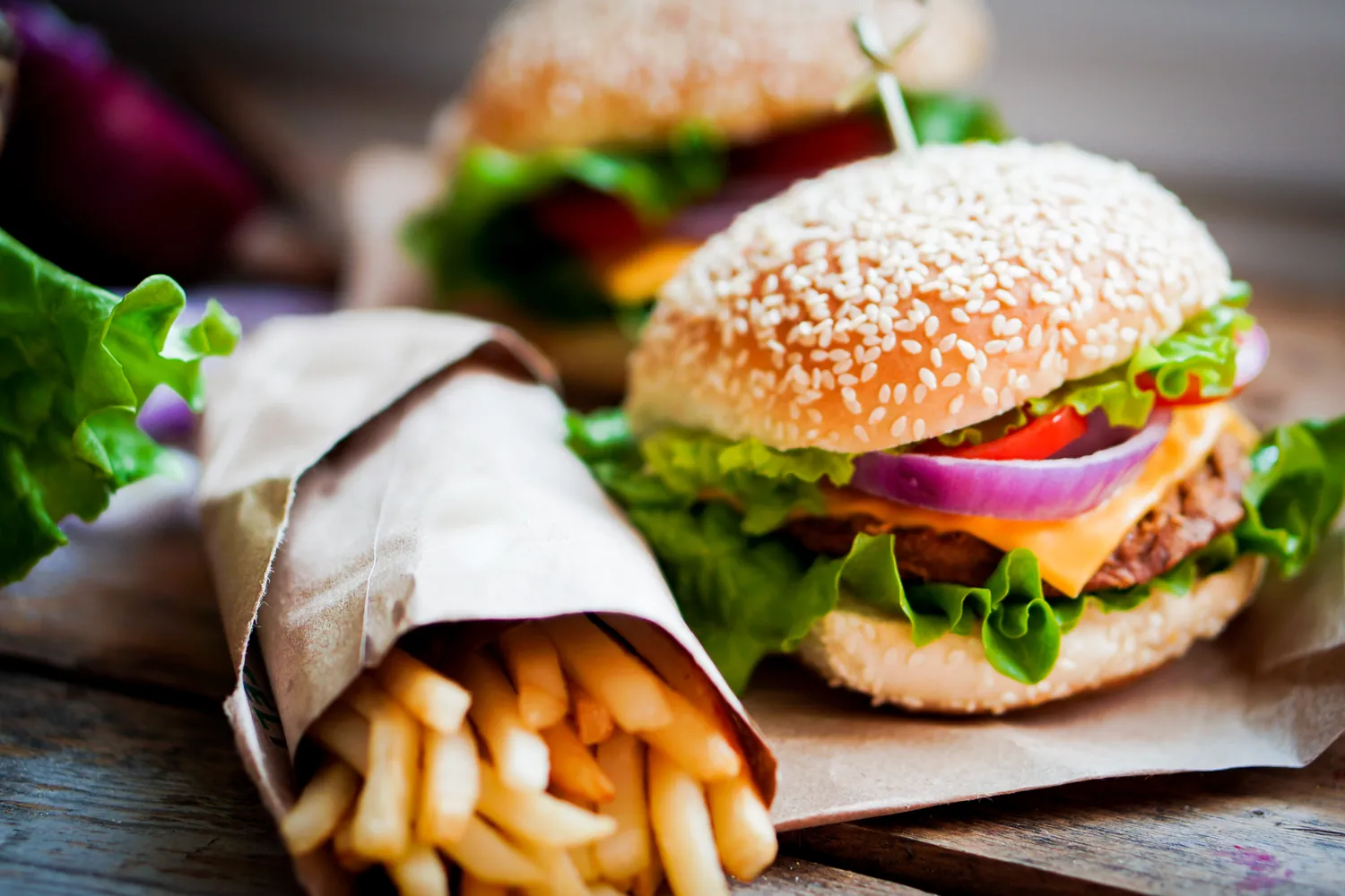 A burger and chips wrapped in paper on a wooden board
